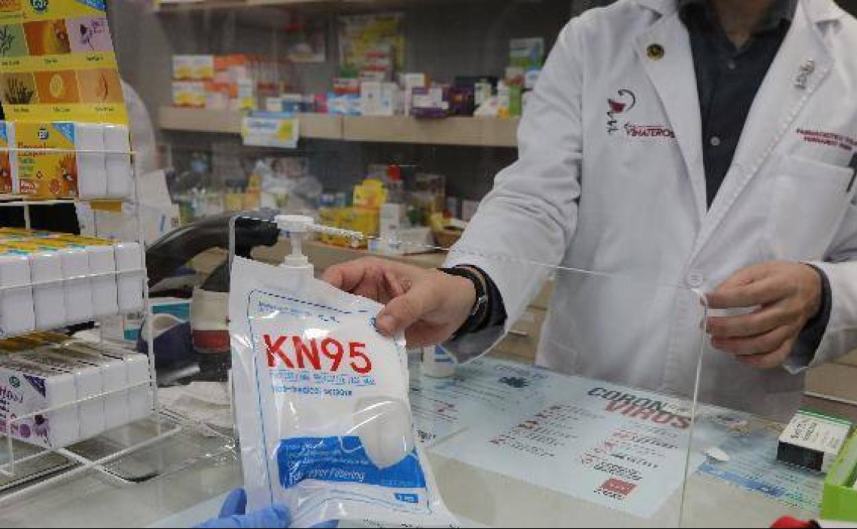 Un farmacéutico vende una mascarilla KN95 en su farmacia