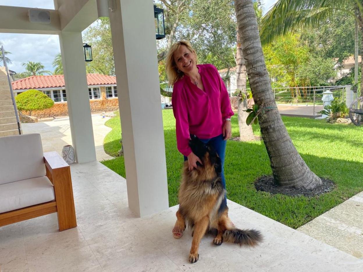 La asturiana Rosa María en el jardín de su casa de Miami, junto a su perro. 