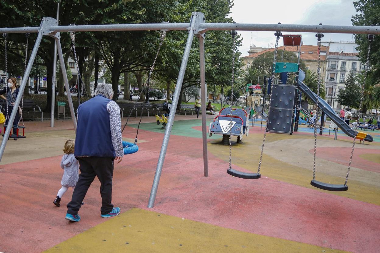 Una mujer lleva de la mano a una niña mientras caminan por el parque del paseo de Begoña, en Gijón. 