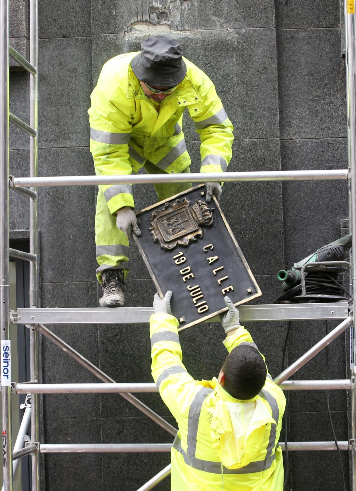 Operarios cambiando, en 2018, la placa de la calle 19 de Julio, que ahora se denomina Progreso, tras la intervención del tripartito. 