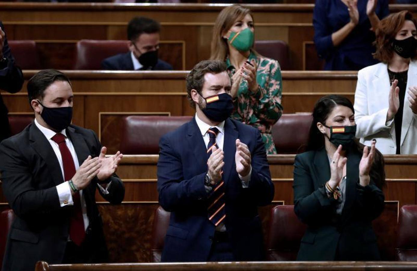 El líder de Vox, Santiago Abascal (i) junto a Iván Espinosa de los Monteros y Macarena Olona (d) aplauden la intervención de Garriga.