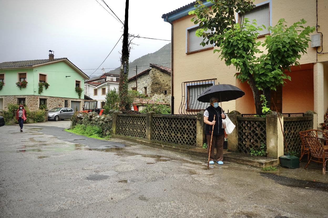 Una vecina pasea bajo la lluvia por las calles de Sobrefoz, localidad del concejo de Ponga. 