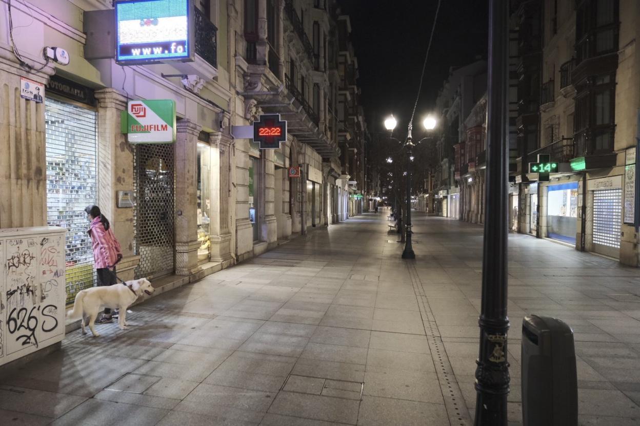 Una vecina pasea al perro en una desierta calle Corrida, en Gijón. 