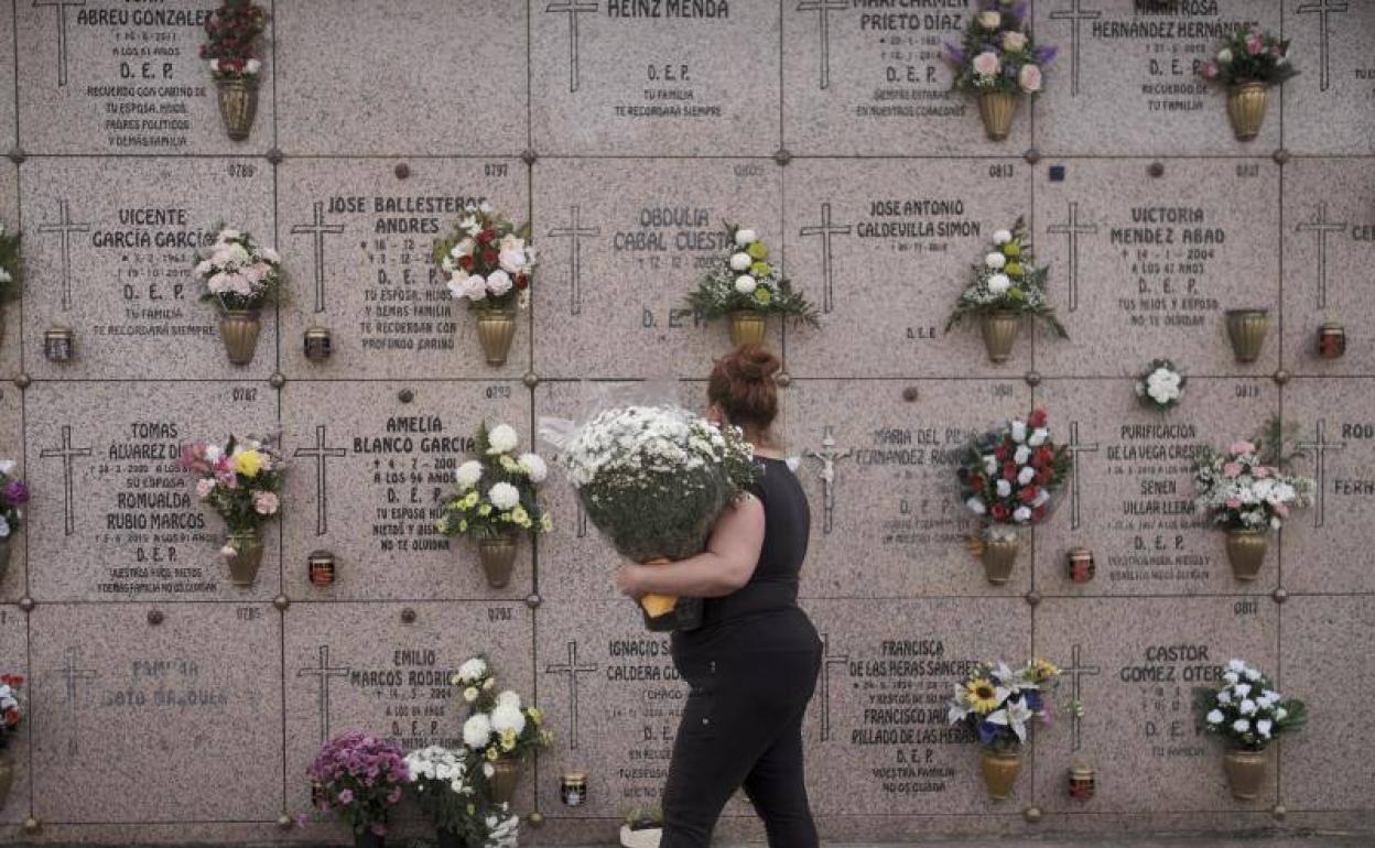 Una mujer, con flores en el cementerio de Deva. 