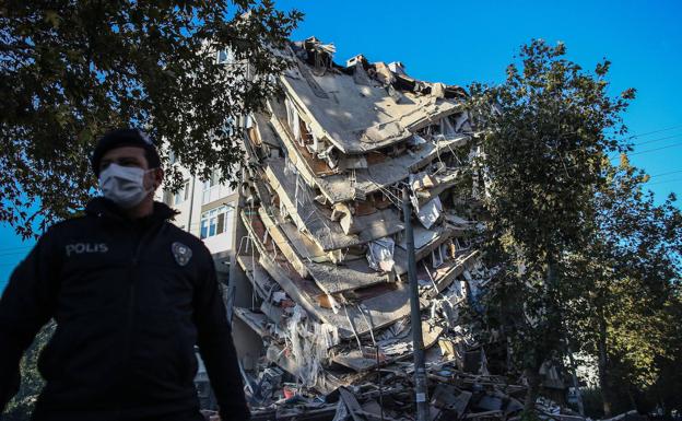 Un policía acordona la zona junto a un edificio derrumbado.