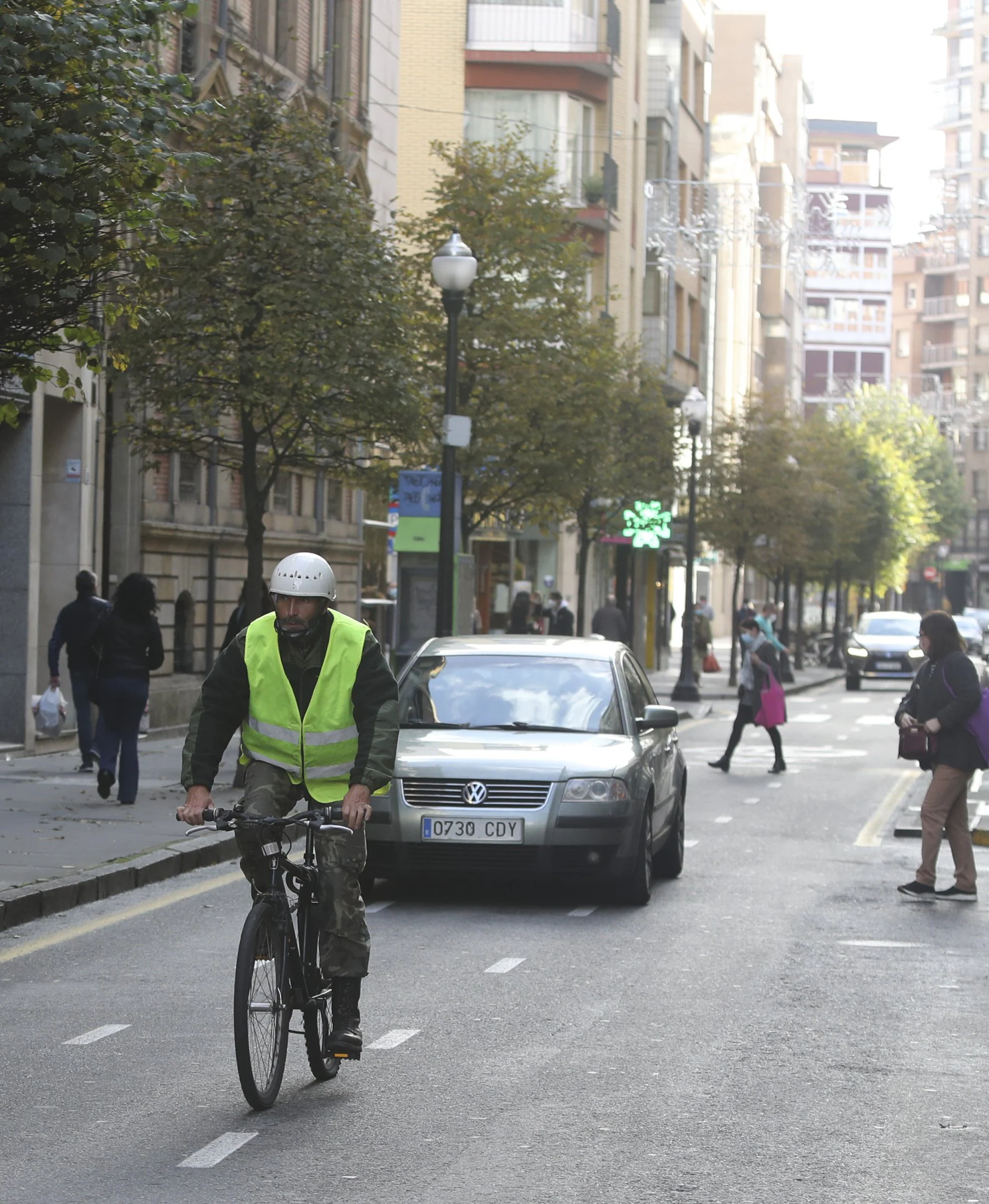 Un usuario del ciclocarril de la calle Uría, seguido por un coche.