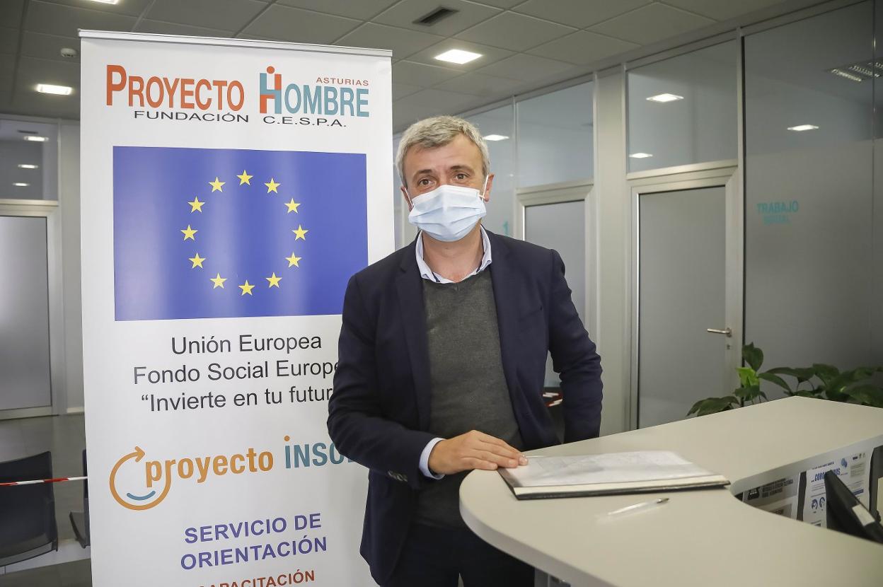 Julio Jonte, director de Proyecto Hombre en Asturias, posa en su oficina de Gijón, mostrando el cartel del programa de reinserción 'Proyecto Insola'. 