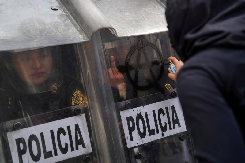 Una oficial de policía realiza un corte de mangas cuando miembro de un colectivo feminista pinta el símbolo anarquista en su escudo durante una marcha para conmemorar el Día Internacional del Aborto Seguro en la Ciudad de México, México, el 27 de septiembre de 2020. 