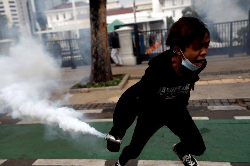 Un manifestante a punto de devolverle a la policía un bote de gas lacrimógeno durante una protesta contra la nueva ley de ómnibus, en Yakarta, Indonesia, el 13 de octubre de 2020. 