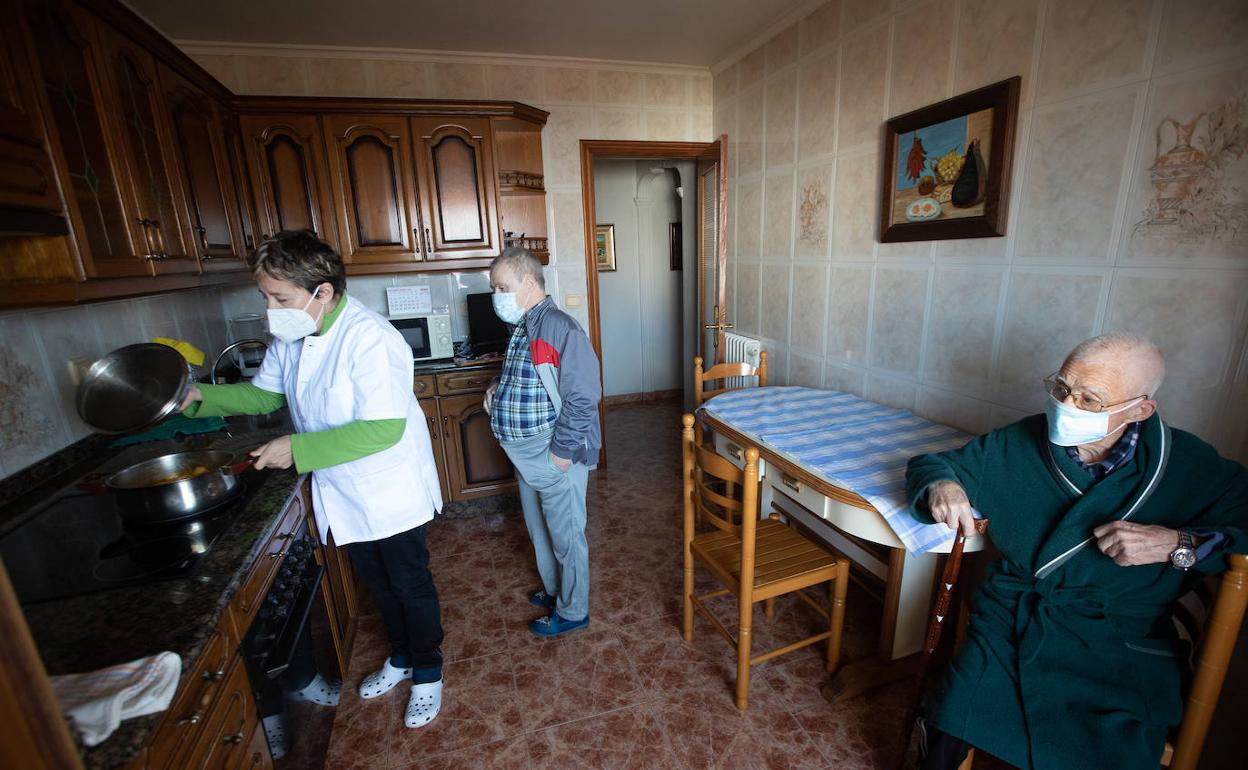 Lucía Francés prepara la comida en presencia de Jaime, de 92 años, y su hijo Carlos, de 54, con síndrome de Down, en Las Vegas, Corvera. 