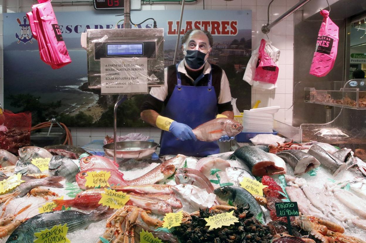 El propietario de Pescados Lastres, en el Mercado del Sur, en Gijón, con un besugo. 