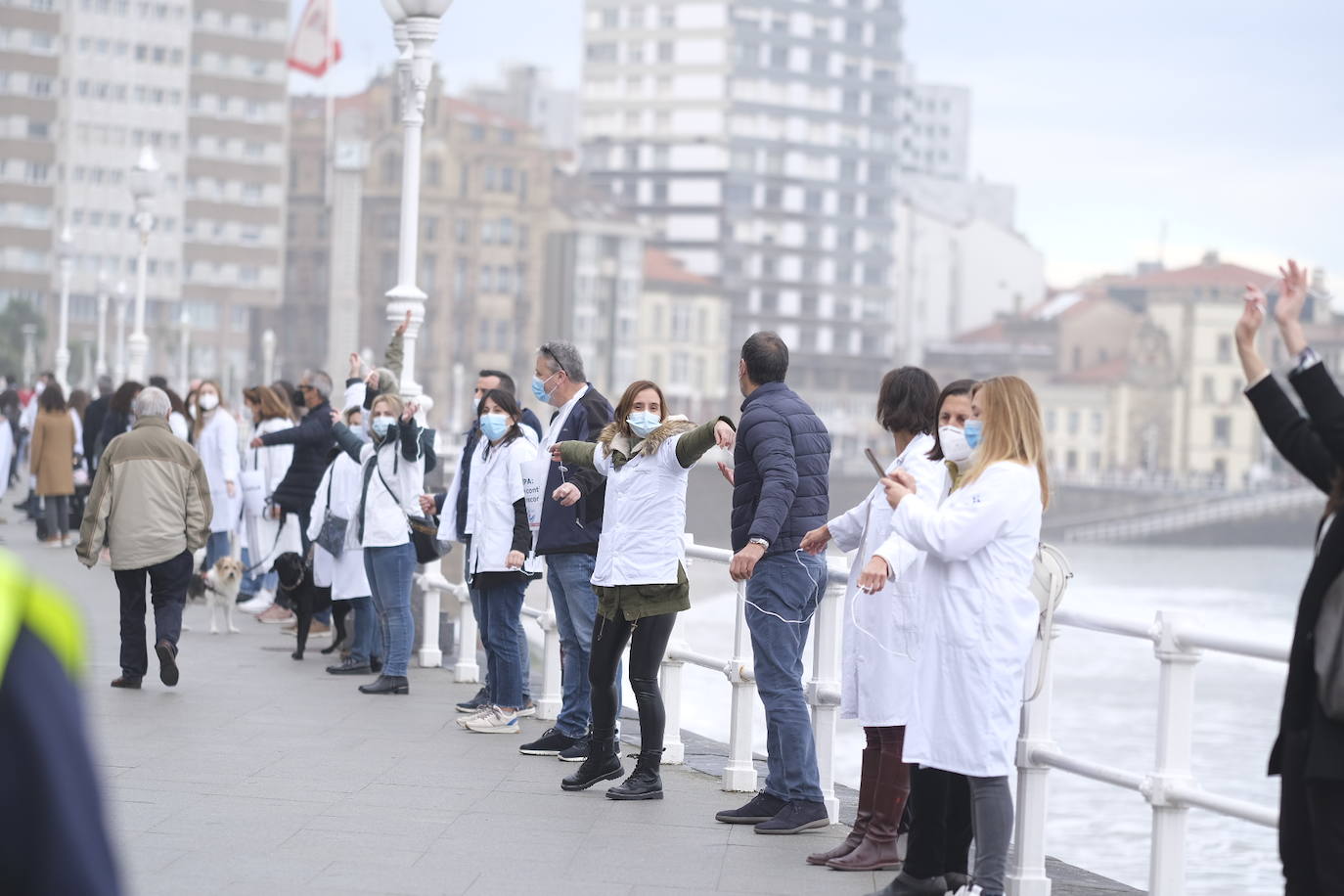 Decenas de personas se han sumado a una cadena humana en el muro de San Lorenzo, en Gijón. Se trata de una iniciativa en defensa de la sanidad pública.