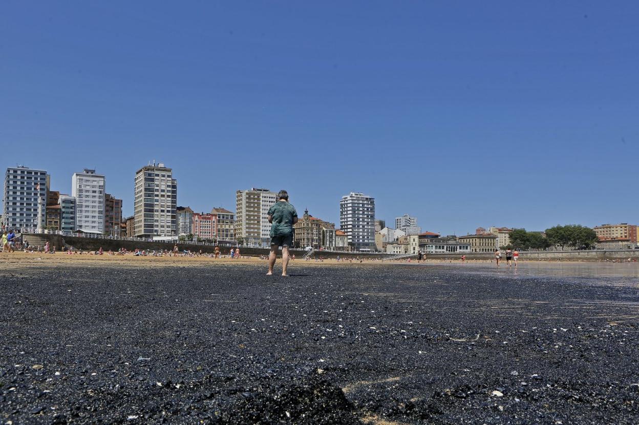 Una de las manchas de carbón que suelen aparecer en el arenal de San Lorenzo. 