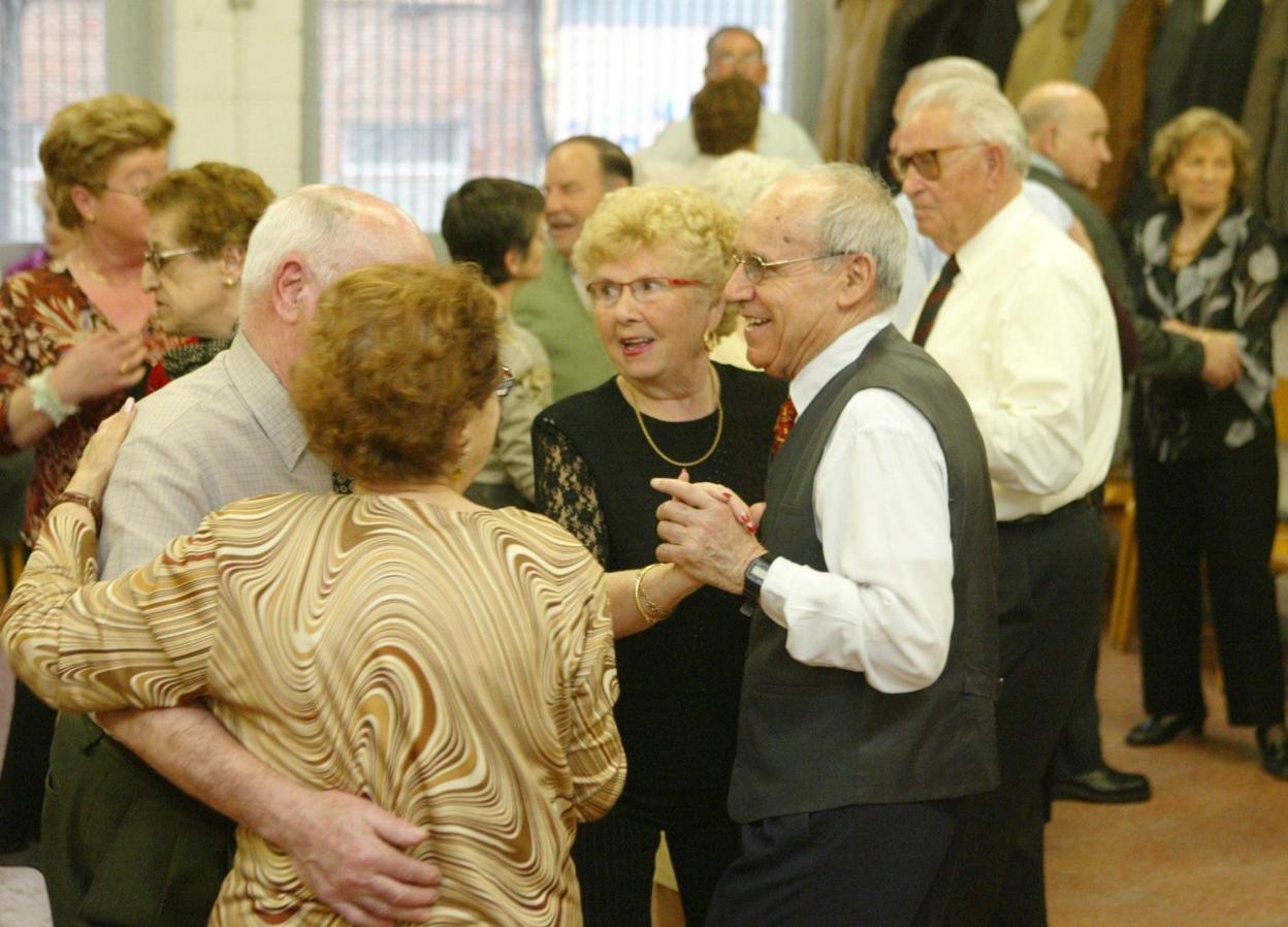 Un grupo de jubilados bailan en un centro de mayores. 