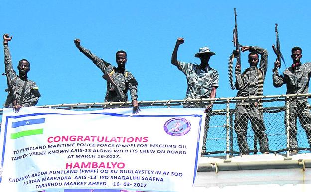 Imagen principal - Policías festejan encaramados a un tanque de petróleo un rescate marítimo. Abajo, una vendedera callejera de gasolina en Mogadishu y una mujer de de beber a un nño desnutrido.