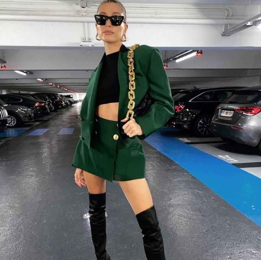 Hailey Bieber como cada año ha vuelto a convertir en protagonistas todos y cada uno de los looks que le hemos visto este 2020. Looks que llevan integrado ese toque tan personal de la modelo y que están repletos de prendas divertidas como este conjunto en color verde con top cropped negro, botas de caña muy alta negras y mini bolso con cadena XXL.