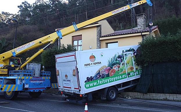 Una grúa intenta extraer el camión de la vivienda. 