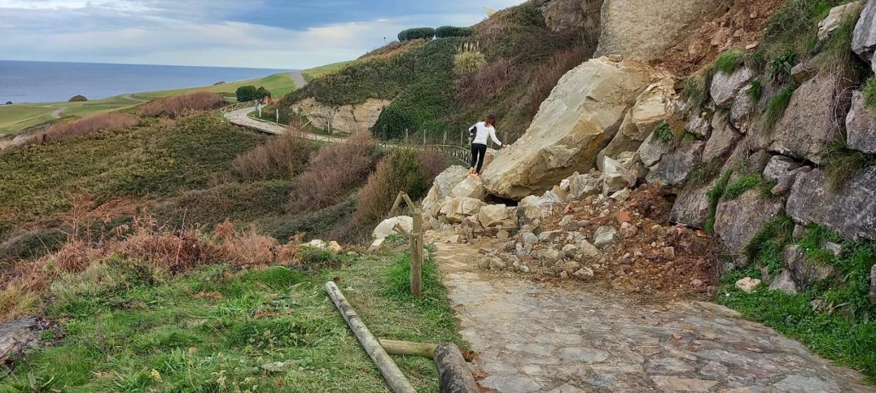 Una mujer cruza sobre las rocas, pese a que el tramo está vallado. 