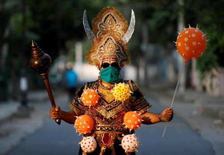 Un residente local vestido como Yamraj, el dios hindú de la muerte, con un collar de globos con temática de coronavirus, hace gestos mientras posa durante una toma de conciencia sobre el distanciamiento social y la permanencia en casa organizada por la policía de Delhi durante un cierre nacional en Nueva Delhi, India.