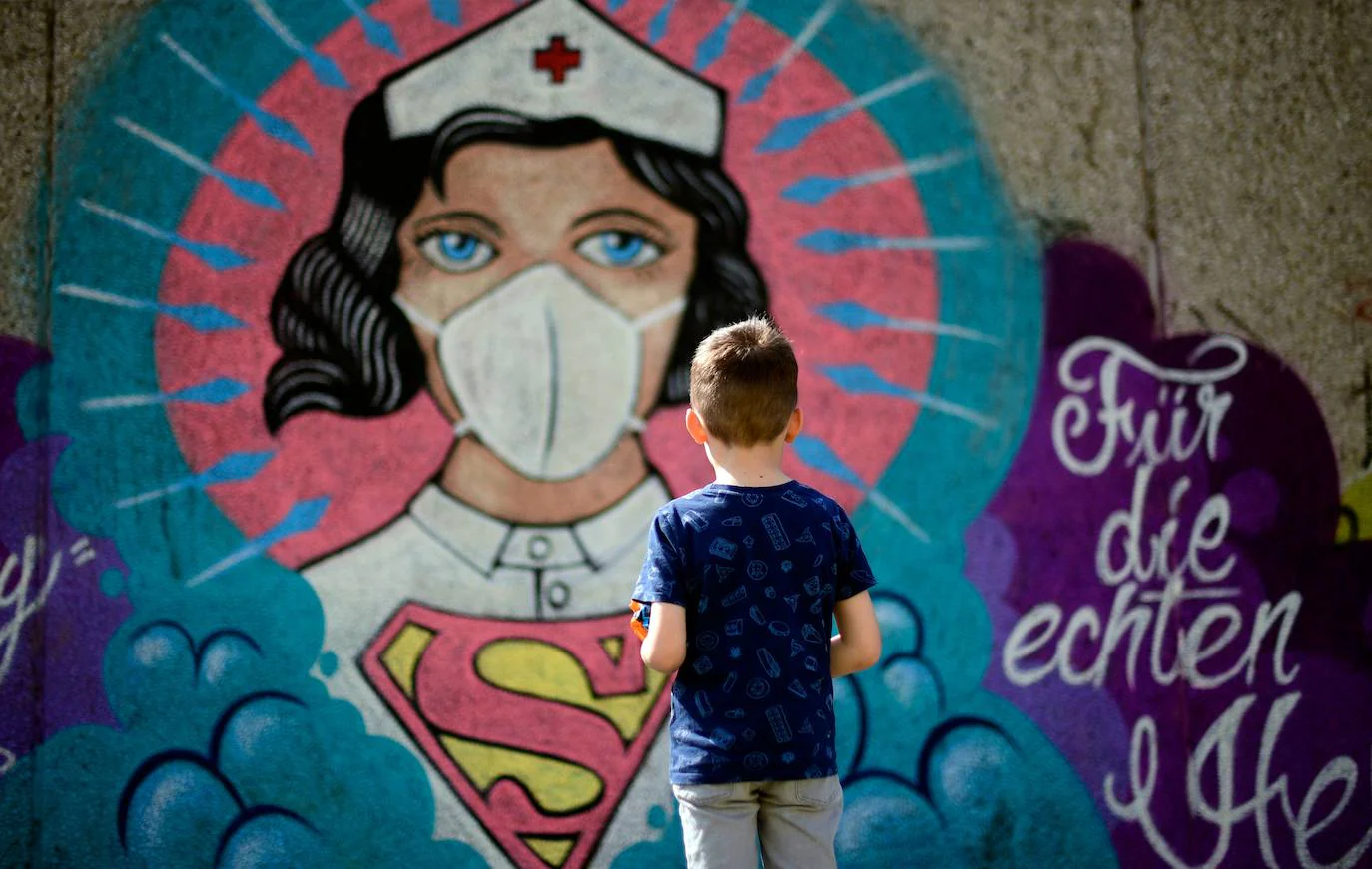 Un niño, frente a un graffiti pintado por el artista Kai 'Uzey' Wohlgemuth que muestra a una enfermera como Superwoman en una pared en Hamm, en el oeste de Alemania