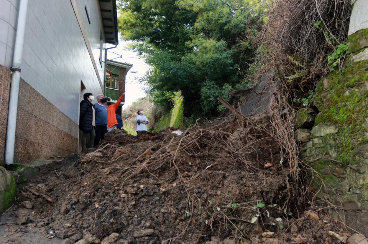 Un grupo de vecinos señala el último argayo que se ha producido en el núcleo de La Crucina, en Turón. 