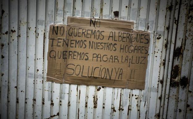 Imagen principal - 1) «No queremos un albergue, queremos luz», es uno de los carteles que se pueden ver en las puertas de las viviendas de Cañada Real. 2) Luz Divina camina hacia su casa. 3) Imagen de una de las conexiones fraudulentas que ponen en peligro a los ciudadanos que malviven en el lugar.