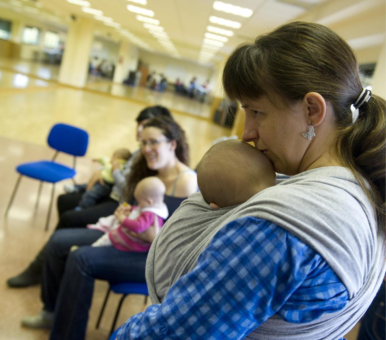 Una madre atiende a su bebé en una actividad de lactantes. 