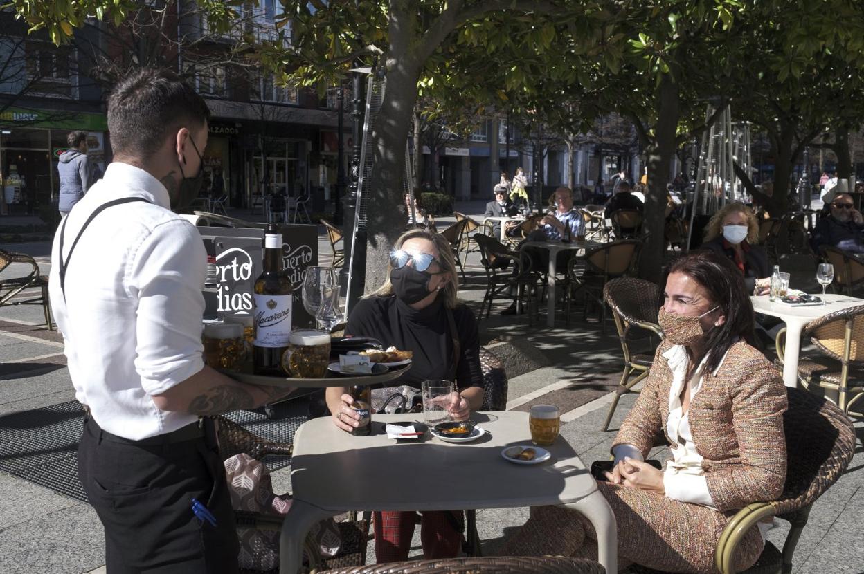 Unas clientas toman un aperitivo en la terraza de un establecimiento hostelero de Gijón. 