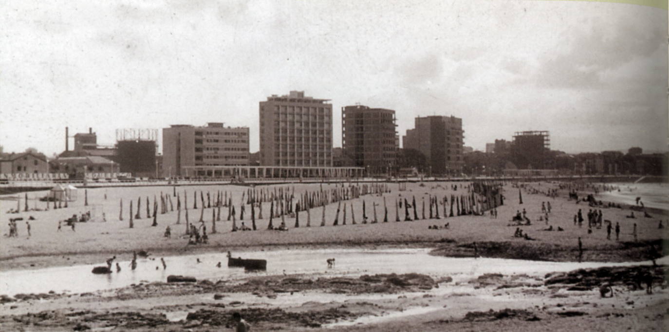 Un paseo por la historia gráfica de la playa de San Lorenzo que arranca con una reproducción de 1900 permite comprobar si el paso de los años han cambiado la orografía y el aspecto del arenal después de que el Ministerio de Transición Ecológica y el Reto Demográfico augurara en un informe que Gijón sufrirá daños anuales de 10 millones por la subida del mar debido al cambio climático