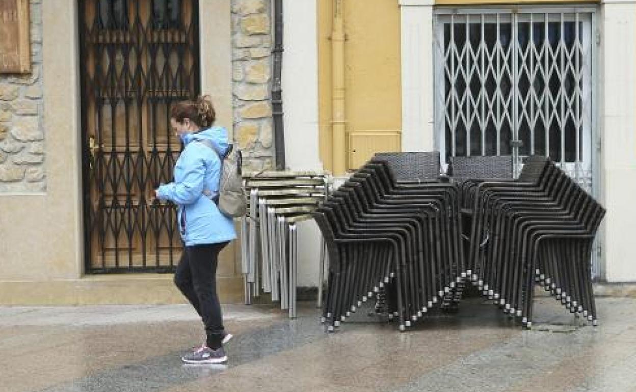 Una mujer pasa por delante de dos negocios cerrados.