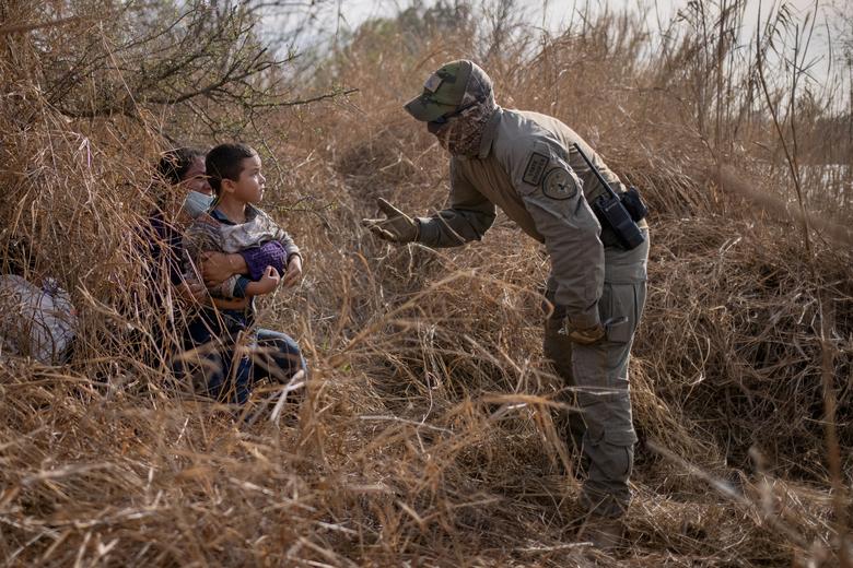 La policía estatal de Texas pide a los migrantes en busca de asilo Edith y su hijo Harbin Ordóñez, de 4 años, que salgan de su escondite después de que los hondureños cruzaron el Río Bravo hacia los Estados Unidos desde México en una balsa en Penitas, Texas.