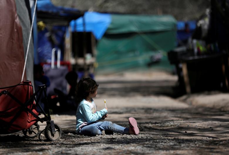 Una niña migrante que viajó con sus padres al norte de México en busca de asilo en los Estados Unidos come una piruleta en un campamento de migrantes en Matamoros.