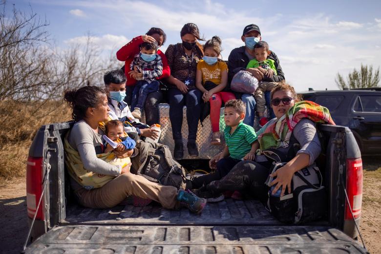 Familias y niños migrantes se sientan en la parte trasera de un camión de la policía para ser transportados después de cruzar el río Grande hacia los Estados Unidos desde México.