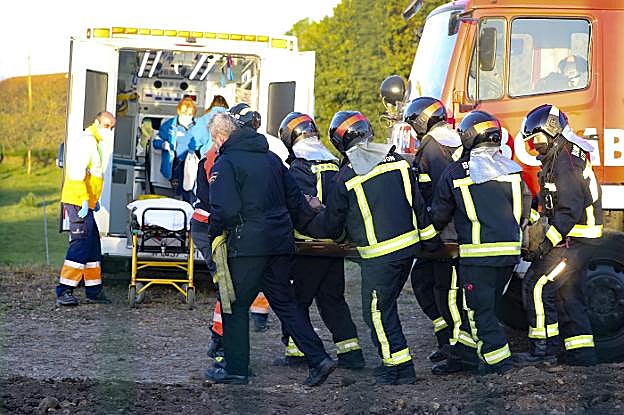 Los bomberos trasladan al herido hasta la ambulancia. 
