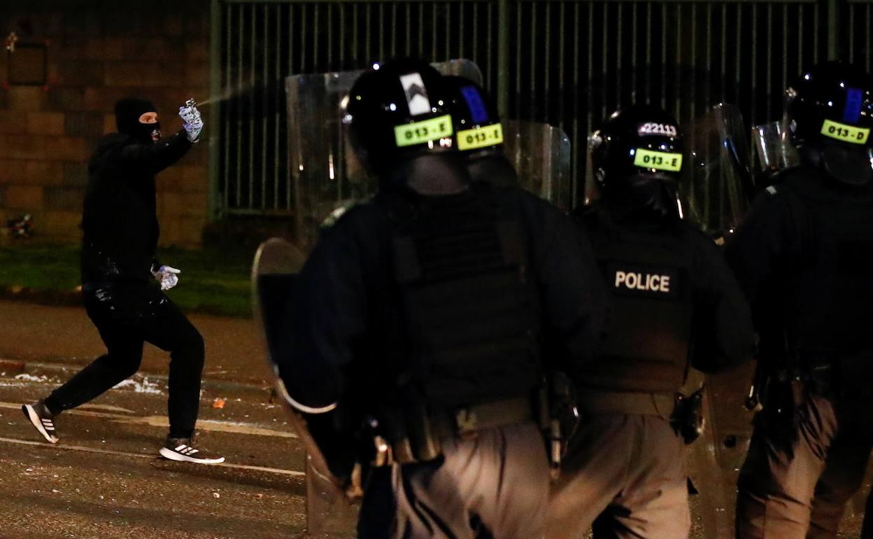 Un encapuchado se enfrenta a la policía en Belfast.