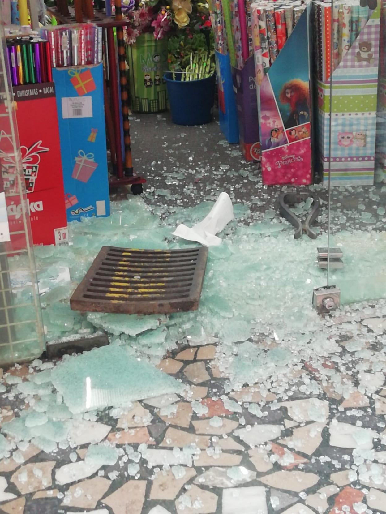 La tapa de alcantarilla con la que los ladrones reventaron los cristales de la puerta del bazar. 