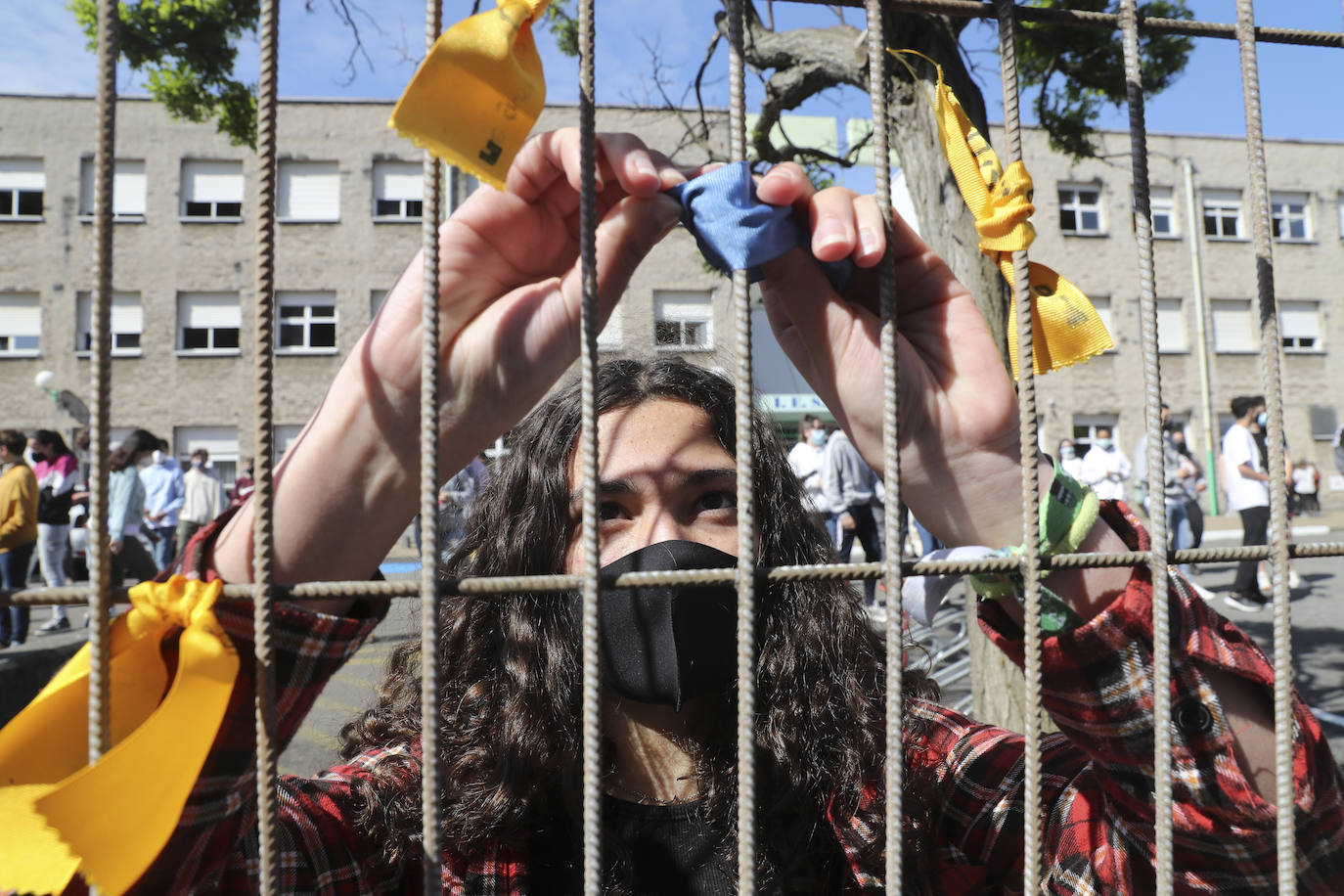 Un total de 150 alumnos han salido de sus clases para realizar un acto en el que los escolares han colocado lazos de colores, que contienen deseos formulados con la ilusión de un viaje, en la valla frontal del patio para formar una cadena de deseos entrelazados.