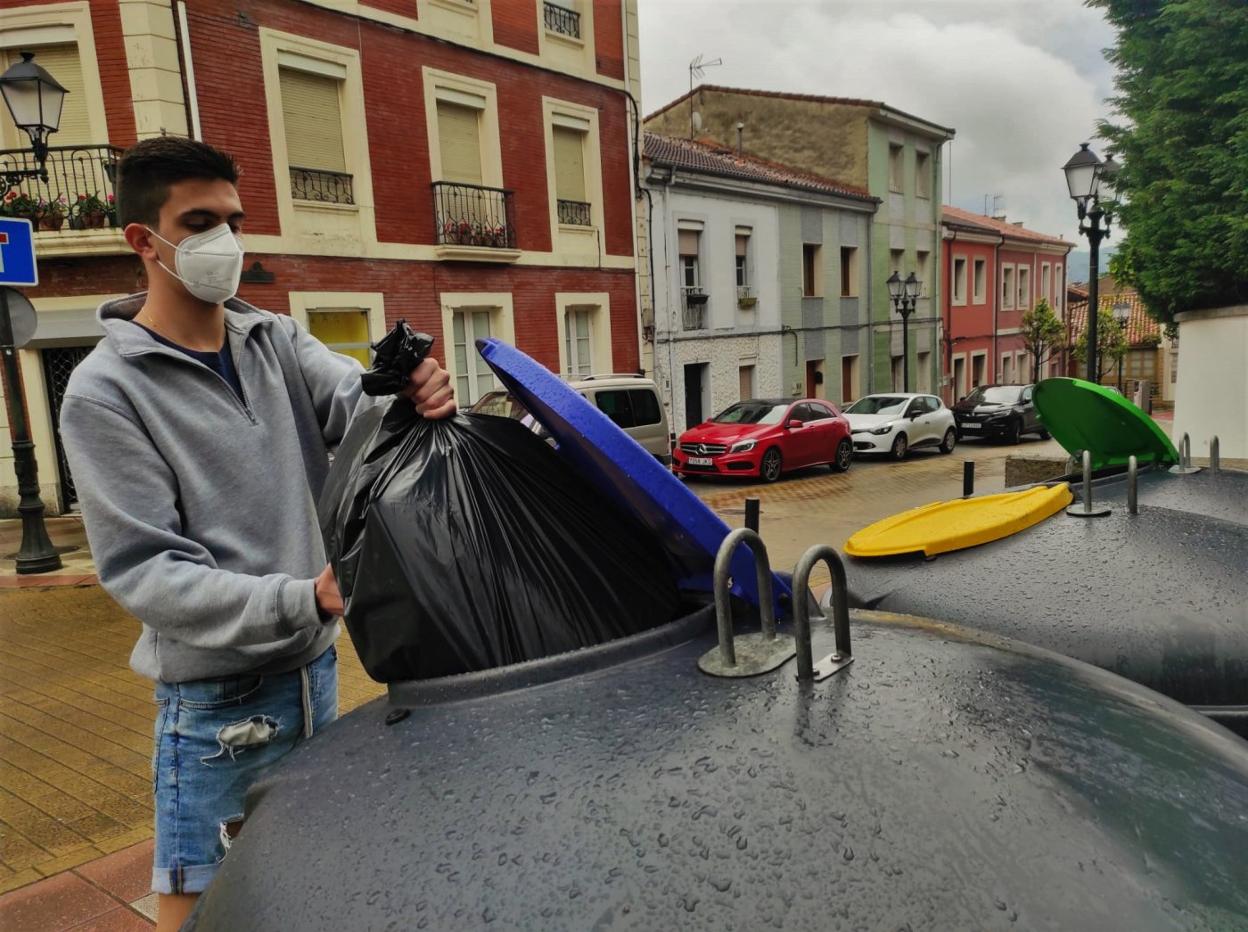 Un joven de la villa condal acude a los contenedores de la Plaza de la Cruz, unos de los más concurridos, para reciclar una bolsa de cartón. 