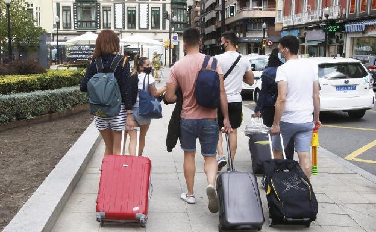 Un grupo de turistas con sus maletas en Gijón. 
