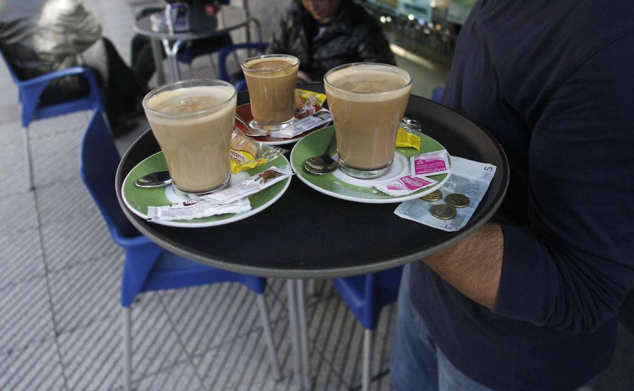 Un camarero con una bandeja de cafés. 