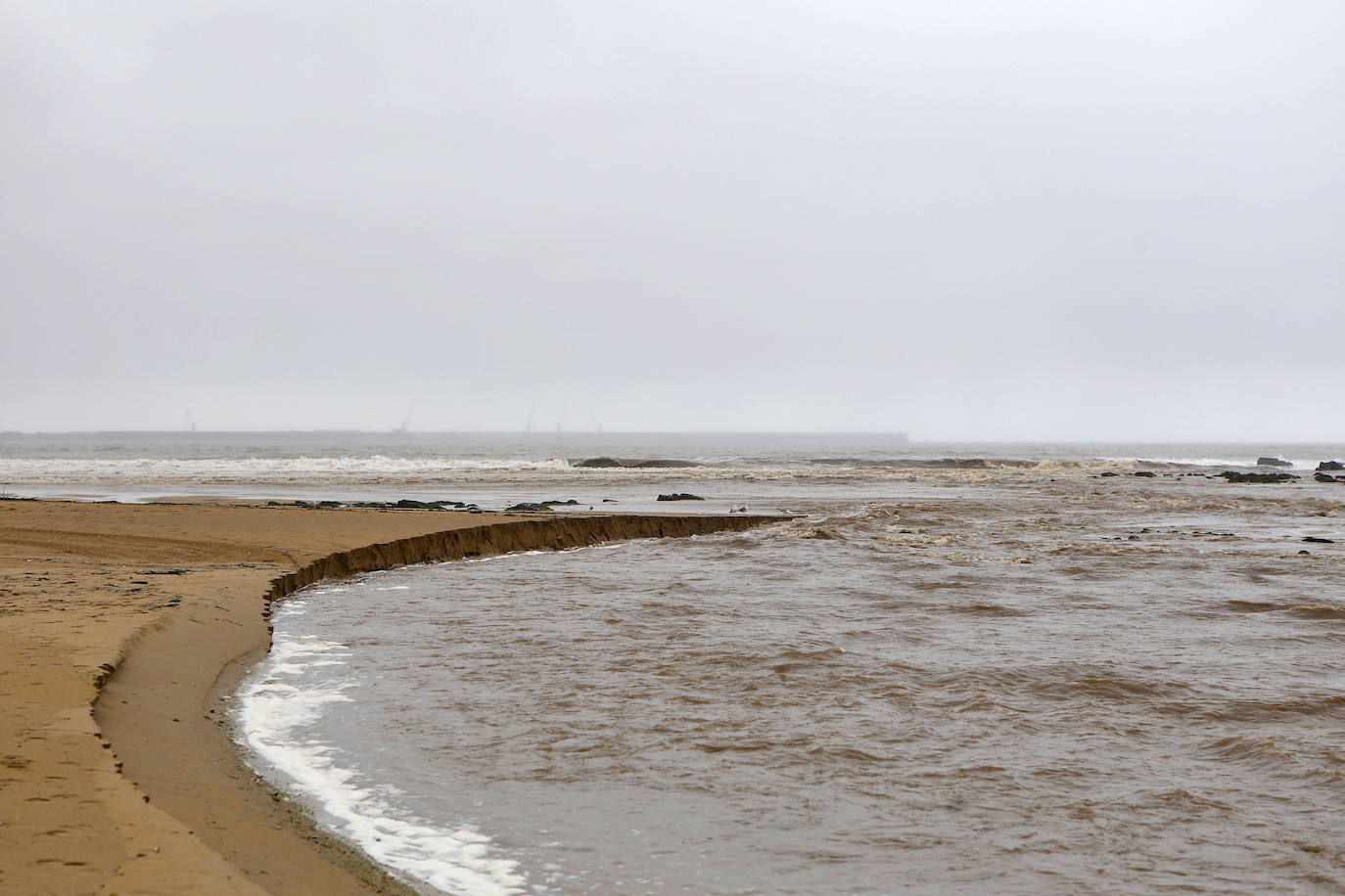 Gijón cierra al baño el tramo entre las escaleras 12 y 15 de la playa de San Lorenzo por los alivios al río Piles provocados por el temporal de lluvias. 