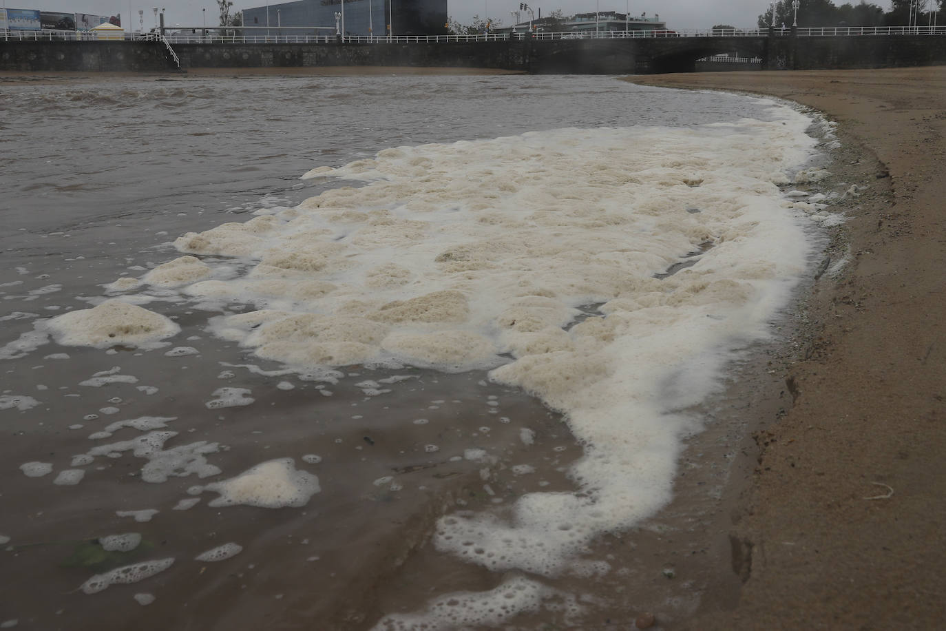 Gijón cierra al baño el tramo entre las escaleras 12 y 15 de la playa de San Lorenzo por los alivios al río Piles provocados por el temporal de lluvias. 