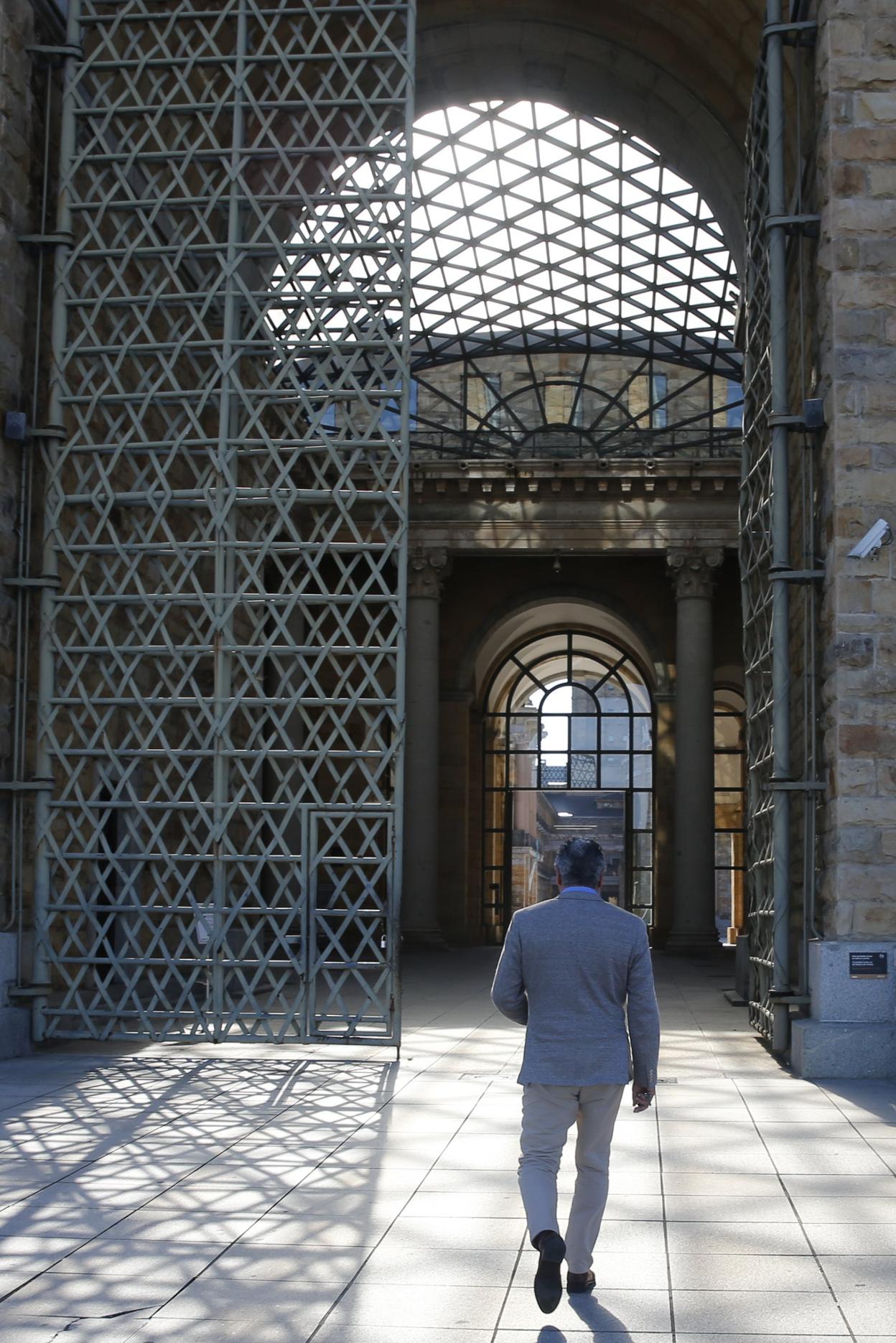 Belarmino Feito camina hacia la puerta del patio central de la Laboral. 