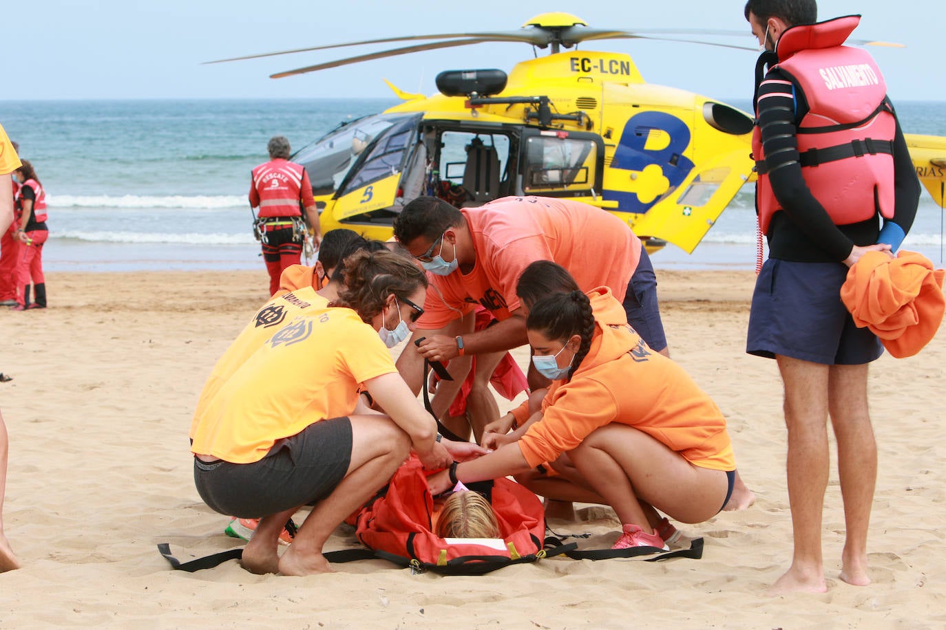 El helicóptero del Servicio de Emergencias del Principado realizó esta mañana un simulacro en la playa de Rodiles. La actuación, que contaba con la participación de más de veinte profesionales, despertó la curiosidad entre los bañistas. El objetivo de este simulacro es enseñar a los socorristas cómo actuar en caso de emergencia durante este verano. El equipo rescatador explicó cuál es la mejor zona para el aterrizaje y cómo deben prepararse.