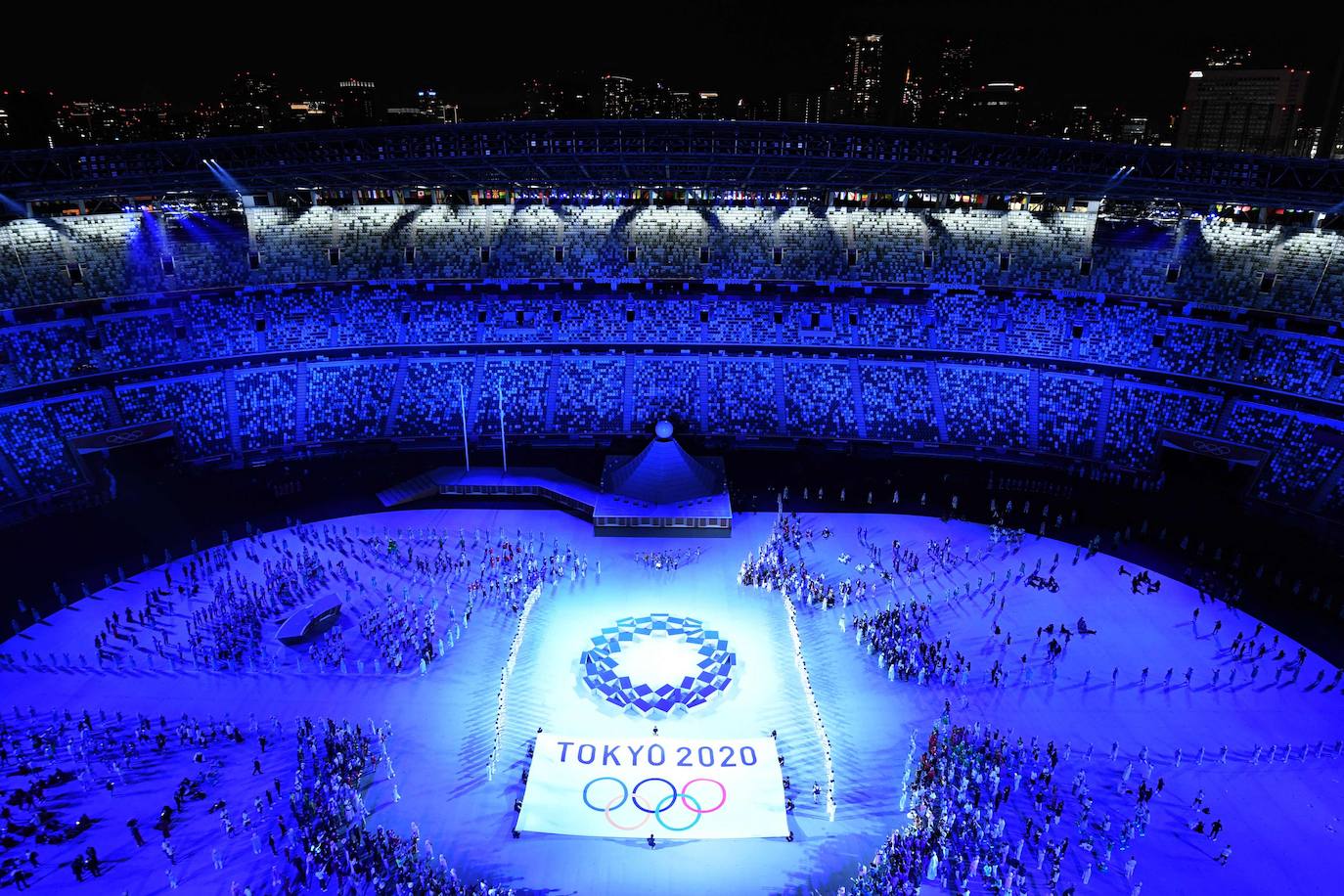 Los Juegos que más se han demorado han dado finalmente arranque tras más de un año. La ceremonia de inauguración, en la que las delegaciones desfilan cada cuatro años ante unas gradas entusiastas, fue en esta ocasión un acto desangelado, debido a la ausencia de público en las competiciones. Sin embargo, algunos rituales se repitieron, como el del encendido del pebetero, uno de los secretos mejor guardados en cada cita y que en esta ocasión consistió en un recipiente esférico inspirado en el Sol. La delegación española, de la que se muestran imágenes, estuvo abanderada por el palista Saúl Craviotto y la nadadora Mireia Belmonte.