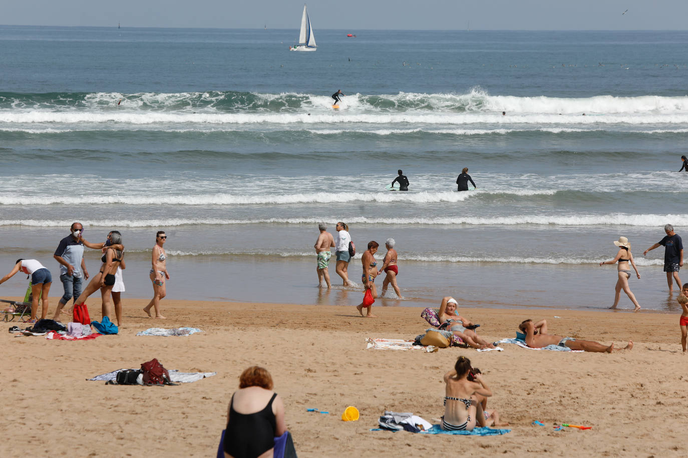 Las temperaturas de este domingo se han quedado lejos de ser las habituales para esta época del año; sin embargo, el sol ha brillado y los gijoneses lo han sabido aprovechar en playas y terrazas 