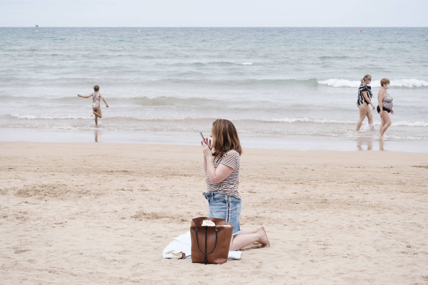 Está siendo un verano atípico en la costa asturiana, pero el mal tiempo no ha impedido que los bañistas se lancen a la playa de San Lorenzo con ganas de disfrutar del día. Algunos pasean, otros leen con la ropa puesta y los más valientes se atreven a darse un chapuzón. Cualquier plan es preferible a quedarse en casa.