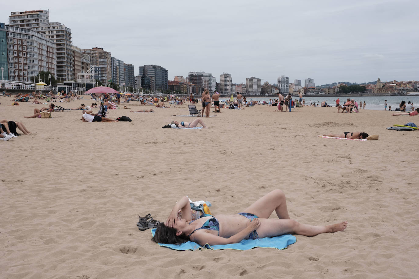 Está siendo un verano atípico en la costa asturiana, pero el mal tiempo no ha impedido que los bañistas se lancen a la playa de San Lorenzo con ganas de disfrutar del día. Algunos pasean, otros leen con la ropa puesta y los más valientes se atreven a darse un chapuzón. Cualquier plan es preferible a quedarse en casa.