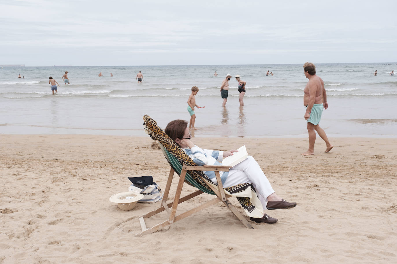 Está siendo un verano atípico en la costa asturiana, pero el mal tiempo no ha impedido que los bañistas se lancen a la playa de San Lorenzo con ganas de disfrutar del día. Algunos pasean, otros leen con la ropa puesta y los más valientes se atreven a darse un chapuzón. Cualquier plan es preferible a quedarse en casa.