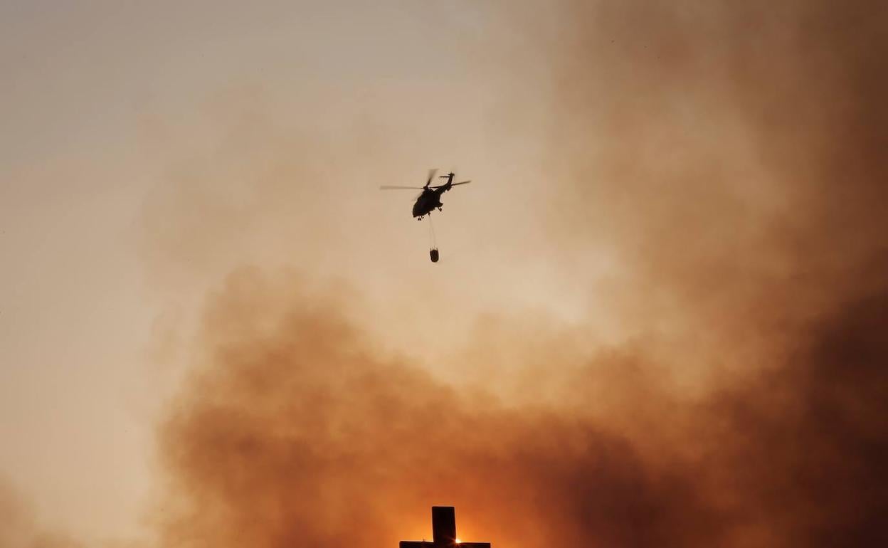 Una cruz cristiana con el fondo de fuego de uno de los incendios que estos días asola Grecia.
